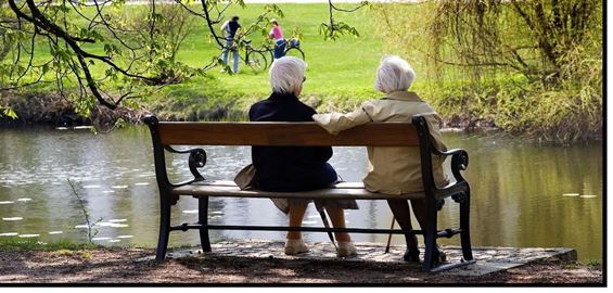To ældre damer, der sidder på en bænk og kigger ud over en sø